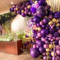 a room filled with lots of purple and gold balloons