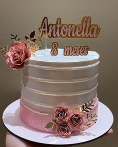 a white cake with pink flowers and gold lettering that says antonella & mex's