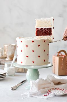 someone is cutting into a heart - patterned cake with a knife on a table next to other desserts