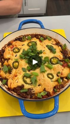 a casserole dish with green peppers and cheese on it sitting on a yellow mat