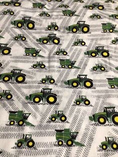 a bed with green tractors on it and yellow wheels in the middle, all over