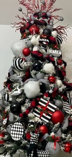 a decorated christmas tree with black and white ornaments on it's top, red and silver decorations around the base