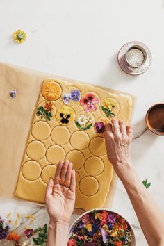 two hands reaching for the dough on top of a table with flowers and other decorations