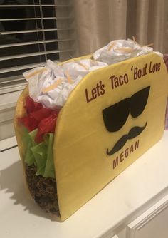 a taco shaped cake sitting on top of a white counter next to a window