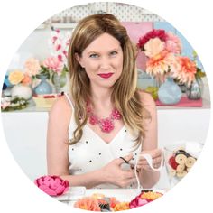 a woman is sitting at a table with some flowers and teddy bears in the background