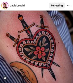 a heart with two swords and a flower in the middle is on someone's thigh