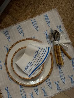 a place setting with blue and white napkins, bamboo utensils and silverware