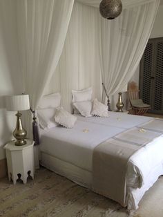 a bed with white sheets and pillows on top of it next to two nightstands