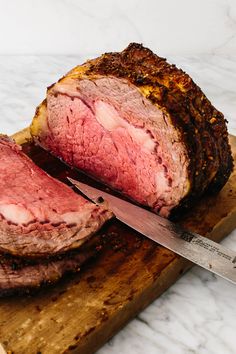 a large piece of meat sitting on top of a cutting board next to a knife