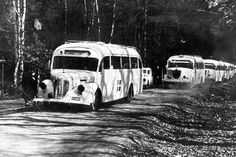 an old black and white photo of three buses on the road with people standing around