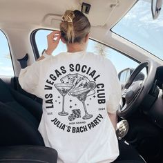 a woman sitting in the back seat of a car wearing a t - shirt that says las vegas social club julia & bach party