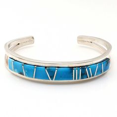 Indulge in the exceptional skill of Navaho artisan Sam Arviso with this meticulously made bracelet featuring Turquoise gemstones inlaid in a striking channel design. With a length of 5 1/4" and 1" opening, this bracelet is precisely crafted and not easily adjustable, ensuring its perfect fit. Its sleek 1/2" width and weight of approximately 27.4 grams make it a stunning and substantial piece for any jewelry collection. Southwestern Style Blue Bangle Bracelets, Southwestern Style Blue Bangle Bracelet, Bohemian Blue Bracelets With Inlay, Elegant Turquoise Bracelet With Inlay, Elegant Turquoise Inlay Bracelet, Artisan Adjustable Blue Sterling Silver Bracelet, Southwestern Turquoise Cuff Bracelet With Inlay, Southwestern Style Turquoise Cuff Bracelet With Inlay, Adjustable Blue Inlay Cuff Bracelet