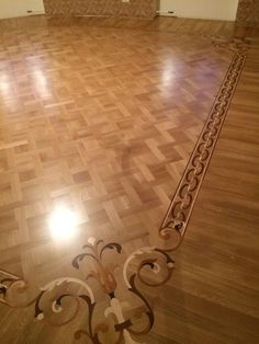 an empty room with hard wood flooring and decorative designs on the floor, looking like it is going to be finished