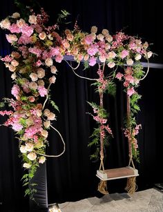 an arrangement of flowers and greenery is displayed on a stage with black drapes