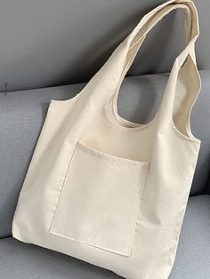 a white bag sitting on top of a couch next to a gray wall and arm rest