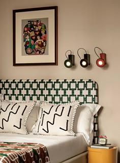 a bed with white sheets and pillows next to two pictures on the wall above it