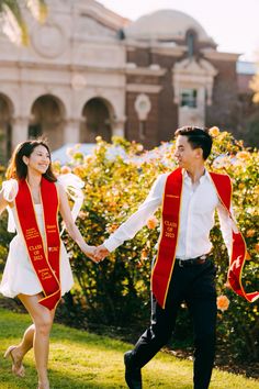 a man and woman holding hands while walking in the grass