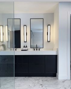 a bathroom with two sinks, mirrors and lights on the wall above them is shown