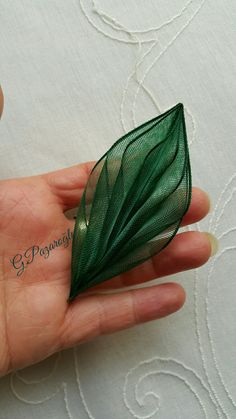 a hand holding a piece of green fabric with leaves on it