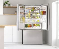 an open refrigerator with its doors wide open in a white kitchen, filled with food and drinks