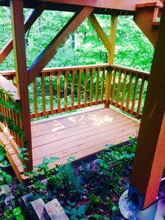 a wooden gazebo sitting on top of a lush green forest covered in leaves and flowers