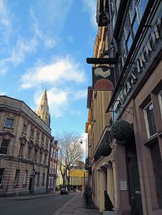 an empty city street with buildings on both sides and a clock tower in the background