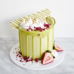 a green cake with strawberries and whipped cream