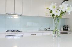 a vase filled with white flowers sitting on top of a counter next to a stove