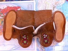 a pair of brown sheepskins with embroidered flowers on the inside and outside, sitting on a map