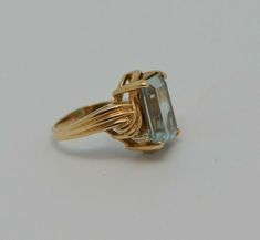 "14K YG Aquamarine rectangle cut with diamond accents. Central stone 10 x 15 mm, Emerald cut Aquamarine, measures 3/4\" across ring, Circa 1960, ring size 7.25, weight 4.8 grams Stock # BRT2046 Most rings are sizable for a small fee. If the ring you are considering is the incorrect size contact us for a quote. This listing contains photographs of the actual item you will receive. Our items are in excellent condition with little or no signs of wear and many are one of a kind pre-owned estate find Modern Gold Topaz Ring In Rectangular Shape, Modern Topaz Ring With Rectangular Stone For Formal Occasions, Rectangular Topaz Ring In Yellow Gold, Modern Formal Topaz Ring With Rectangular Stone, Modern Gold Rectangular Topaz Ring, Modern Yellow Gold Topaz Ring With Rectangular Shape, Rectangular Yellow Gold Topaz Ring, Luxury Rectangular Topaz Anniversary Ring, Formal Topaz Ring With Rectangular Stone