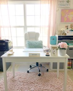 a white desk sitting in front of a window next to a chair and pink rug