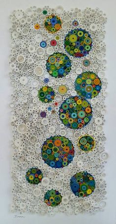 an art work made out of buttons and plastic bottle caps on a white surface with holes in the middle