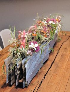 a wooden table topped with lots of flowers on top of each other and plants growing out of it