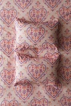 four pillows on top of each other in front of a wallpapered background with an ornate design