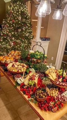 a table covered with lots of food next to a christmas tree