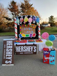 there is a table with candy and candies on it, next to some signs that say hershey's milk chocolate