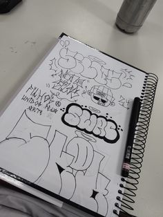 a notebook with graffiti written on it next to a cup of coffee and a pen