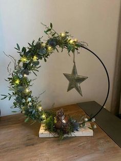 a christmas wreath with lights and greenery on a wooden table next to a metal star