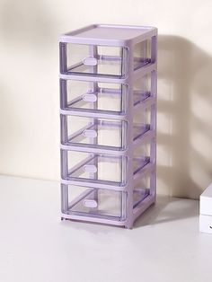 a stack of plastic drawers sitting on top of a white table next to a box