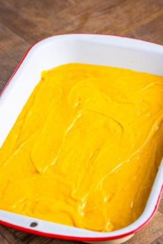 a white dish filled with yellow food on top of a wooden table