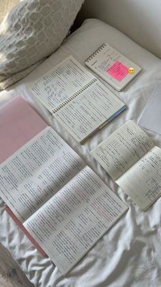 several open notebooks on a bed with pillows