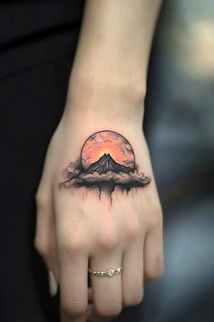 a woman's hand with a tattoo on it and a mountain in the background