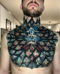 a man with tattoos on his chest is wearing an elaborate piece of art that looks like a peacock