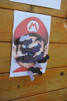 a paper cut out of mario is hanging on the wall next to a piece of paper