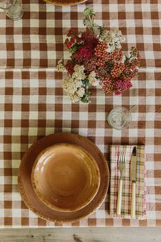 a table topped with a brown plate next to a vase filled with flowers