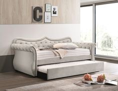 a white daybed sitting on top of a hard wood floor next to a window