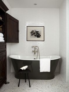 a bathroom with a claw foot bathtub and white towels on the shelf above it