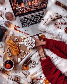 a person sitting in front of a laptop on top of a table with candy canes and marshmallows