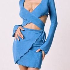 a woman wearing a blue dress with long sleeves and cutouts on the sides, standing in front of a white background