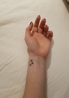 a person's hand with a small tattoo on it, resting on a bed